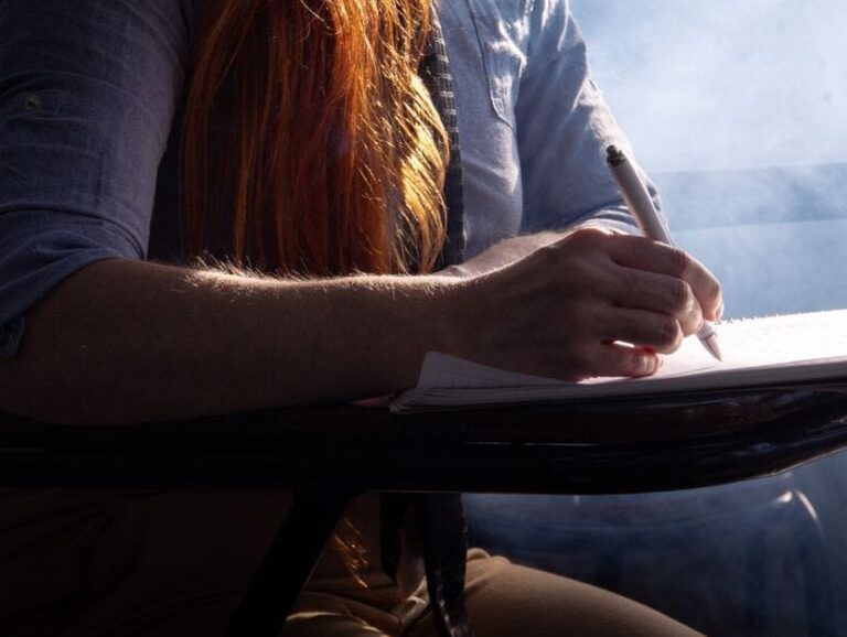 Close-up of a student concentrating on taking notes in a classroom setting with dramatic lighting.